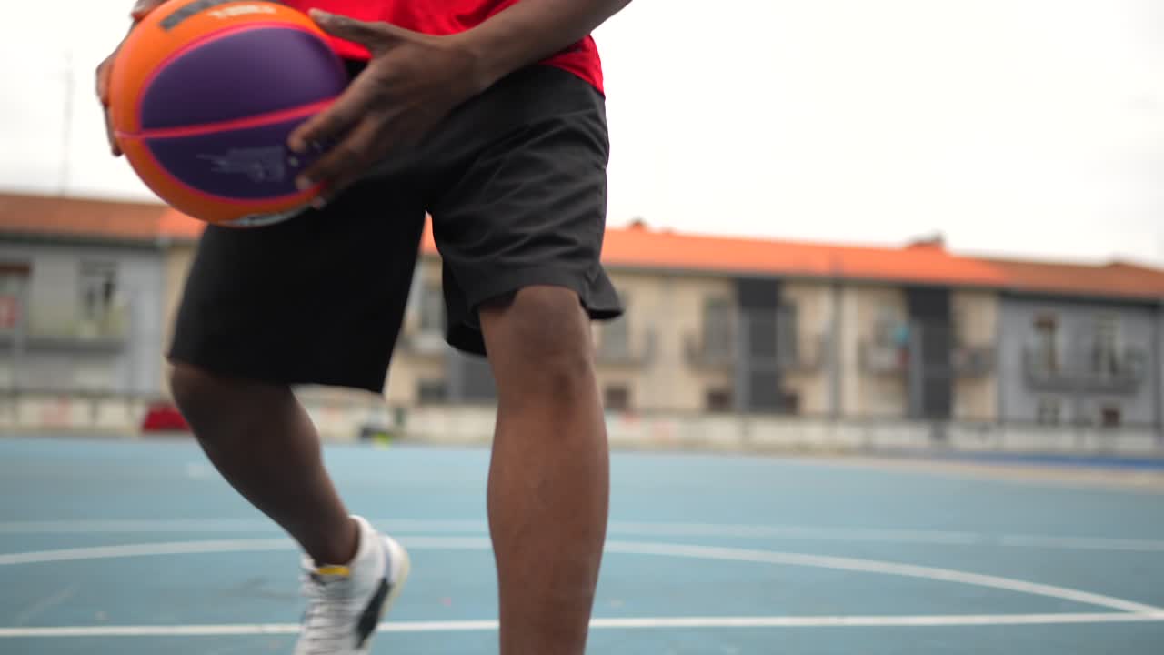 Young man playing basketball on an outdoor court