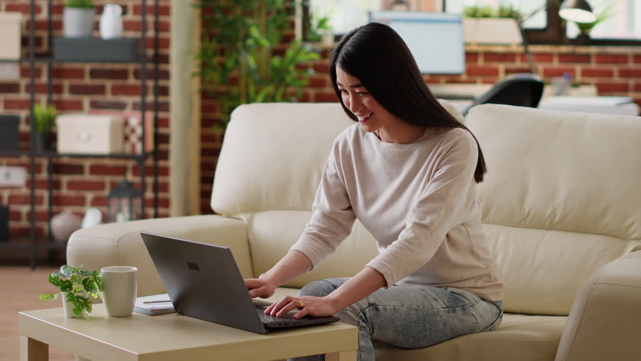 아시아 여성이 집에서 노트북으로 일하고 있습니다.