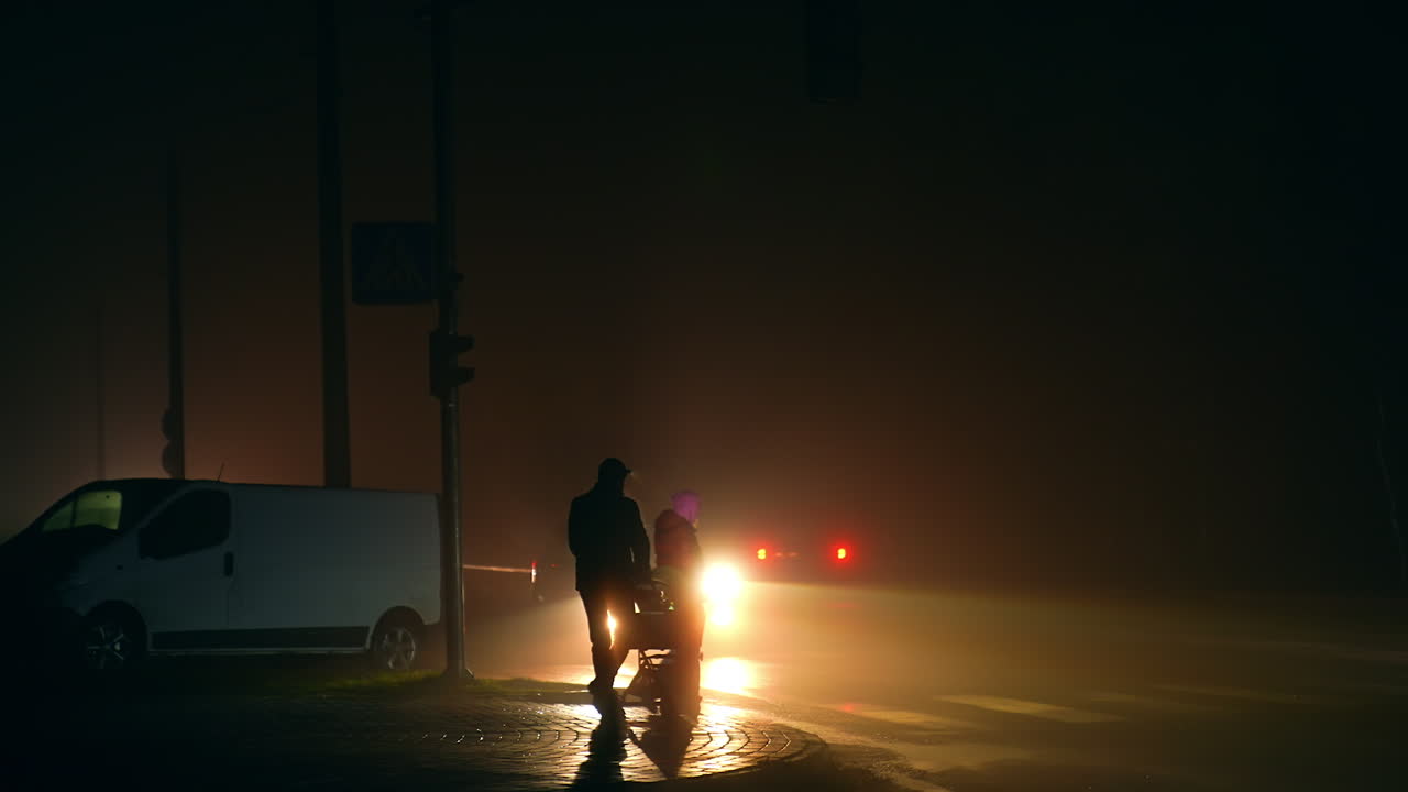 People Crossing a Foggy Street at Night