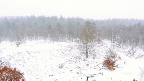 Gente-Caminando-A-Través-De-Una-Vista-De-Bosque-Nevado-En-Una-Tormenta-De-Invierno---Toma-Aérea