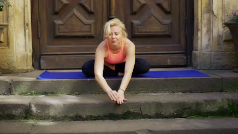 Woman-doing-yoga-over-big-wood-door,-sitting-on-lotus-pose