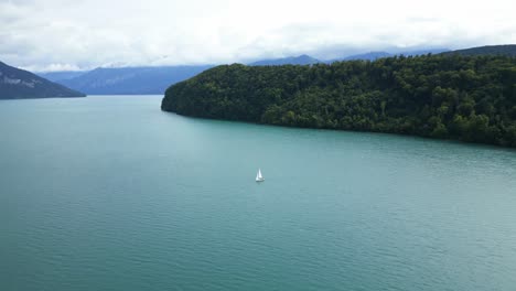 push in drone shot of the bay above thun lake with a white boat sailing in the canton of bern in switzerland.
