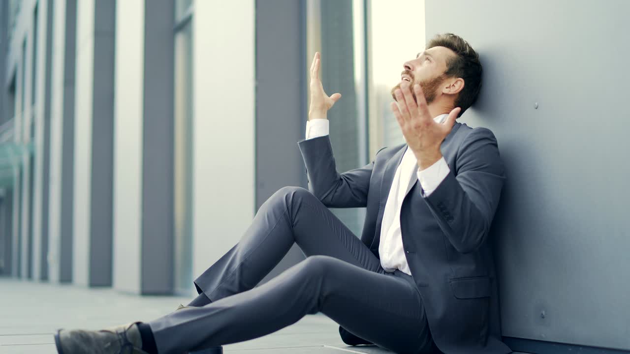 정식복을 입은 우울한 기업가 노동자 남자가 현대 사무실 비즈니스 센터 근처의 야외 거리에 앉아 있습니다.