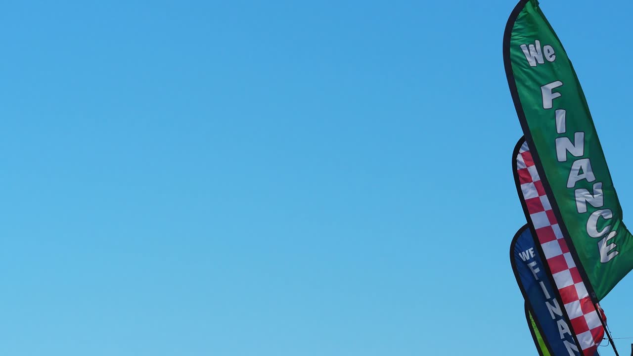 맑고 푸른 하늘을 배경으로 강한 바람에 펄럭이는 다채로운 광고 페넌트