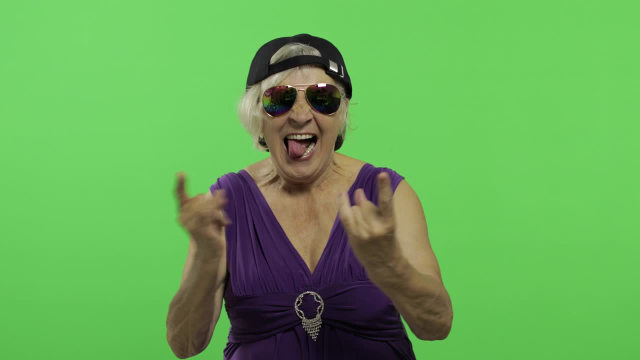 Donna anziana con occhiali da sole che urla con un sorriso e mostra la lingua. Chroma key.
