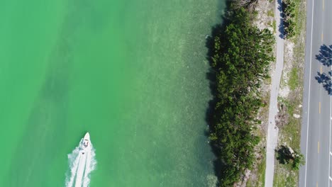 Vista-De-Pájaro-De-Un-Barco-Que-Atraviesa-Los-Cayos-De-Florida-Junto-A-La-Autopista-De-Ultramar