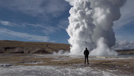 person standing before a giant geothermal steam plume