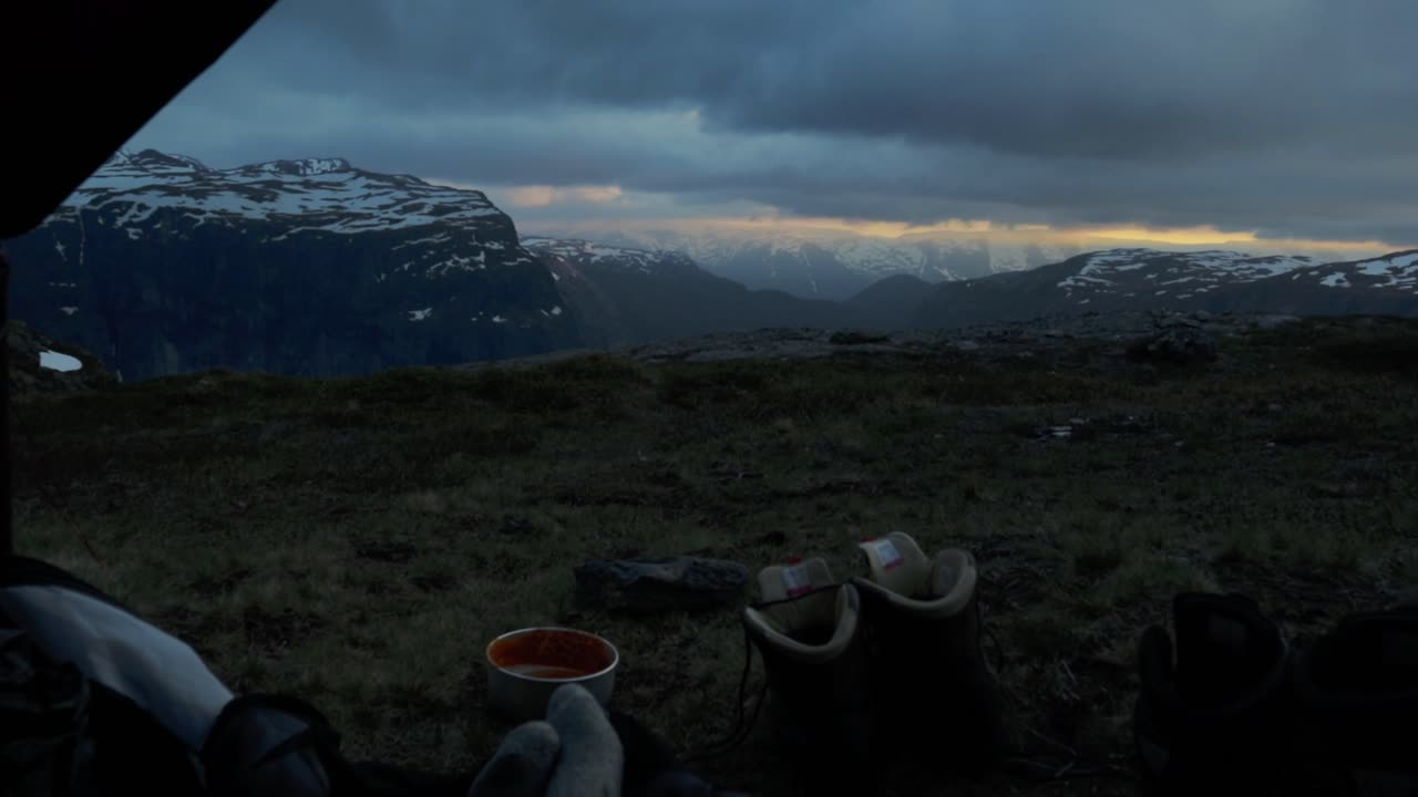 Person resting and camping on Trolltunga, evening view from inside tent