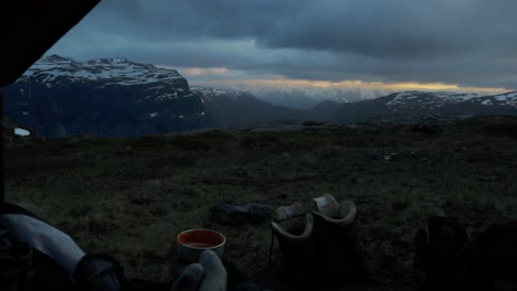 person resting and camping on trolltunga, evening view from inside tent