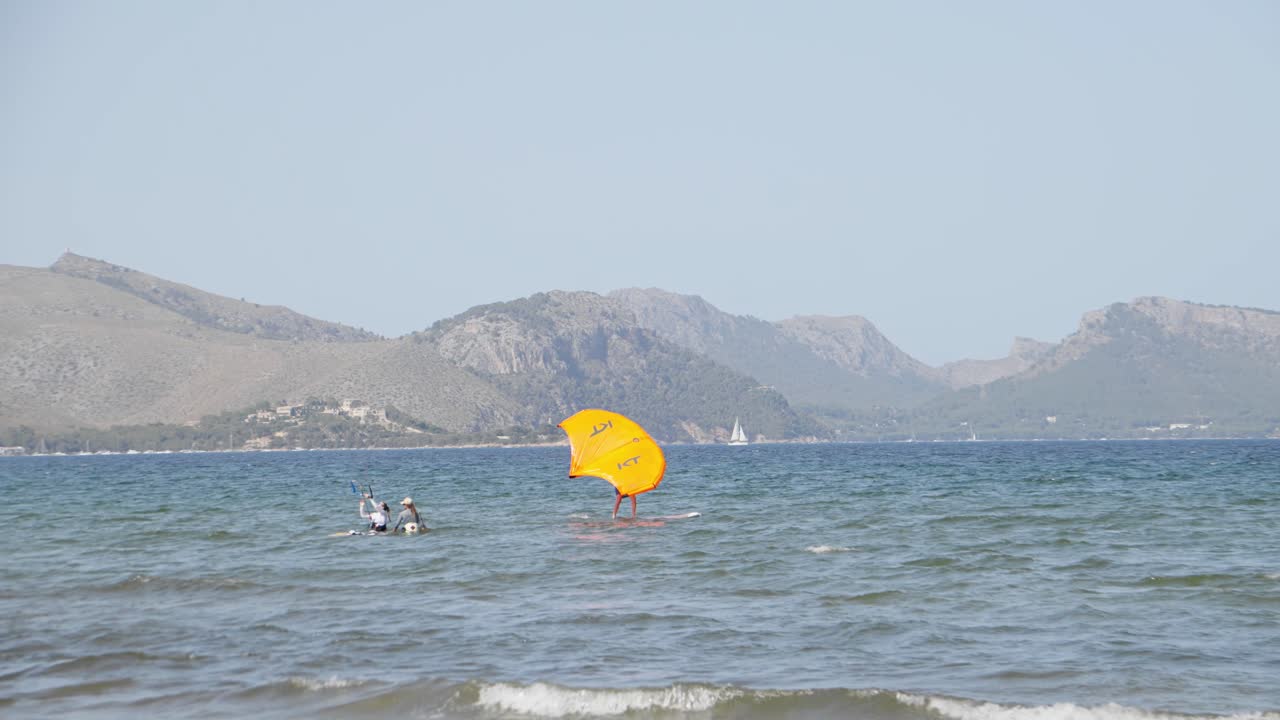 wingfoil surfista en agua azul cear en mallorca islas baleares rodeada de montaña