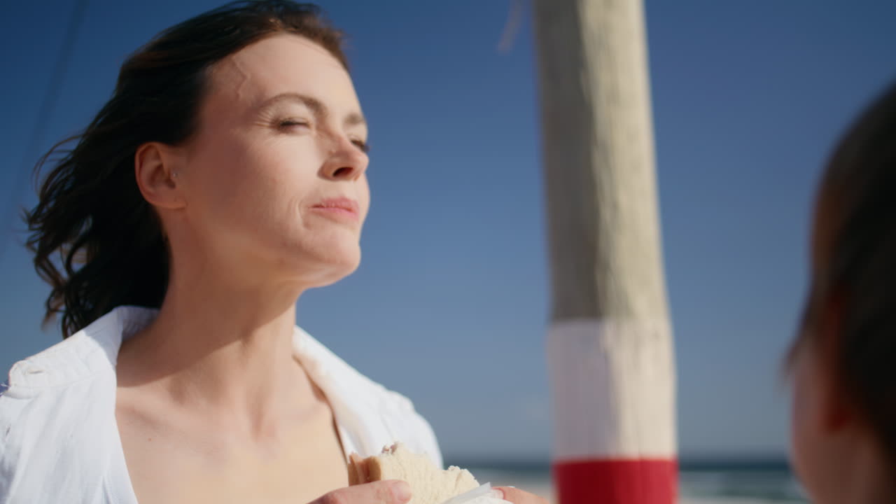 Closeup mother eating sandwich spending weekend with little son at seaside