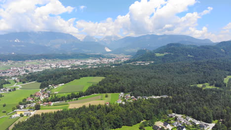 Antenne:-Flug-In-Großer-Höhe-über-Das-Arboretum-In-Volcji-Potok,-Mit-Einem-Riesigen-Wald-Und-Einer-Bergkette-Im-Hintergrund