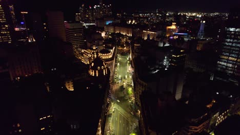 dolly in aerial view of the chaotic city of buenos aires at night with the representative architecture of the rooftops of the icbc bank headquarters and the bencich building