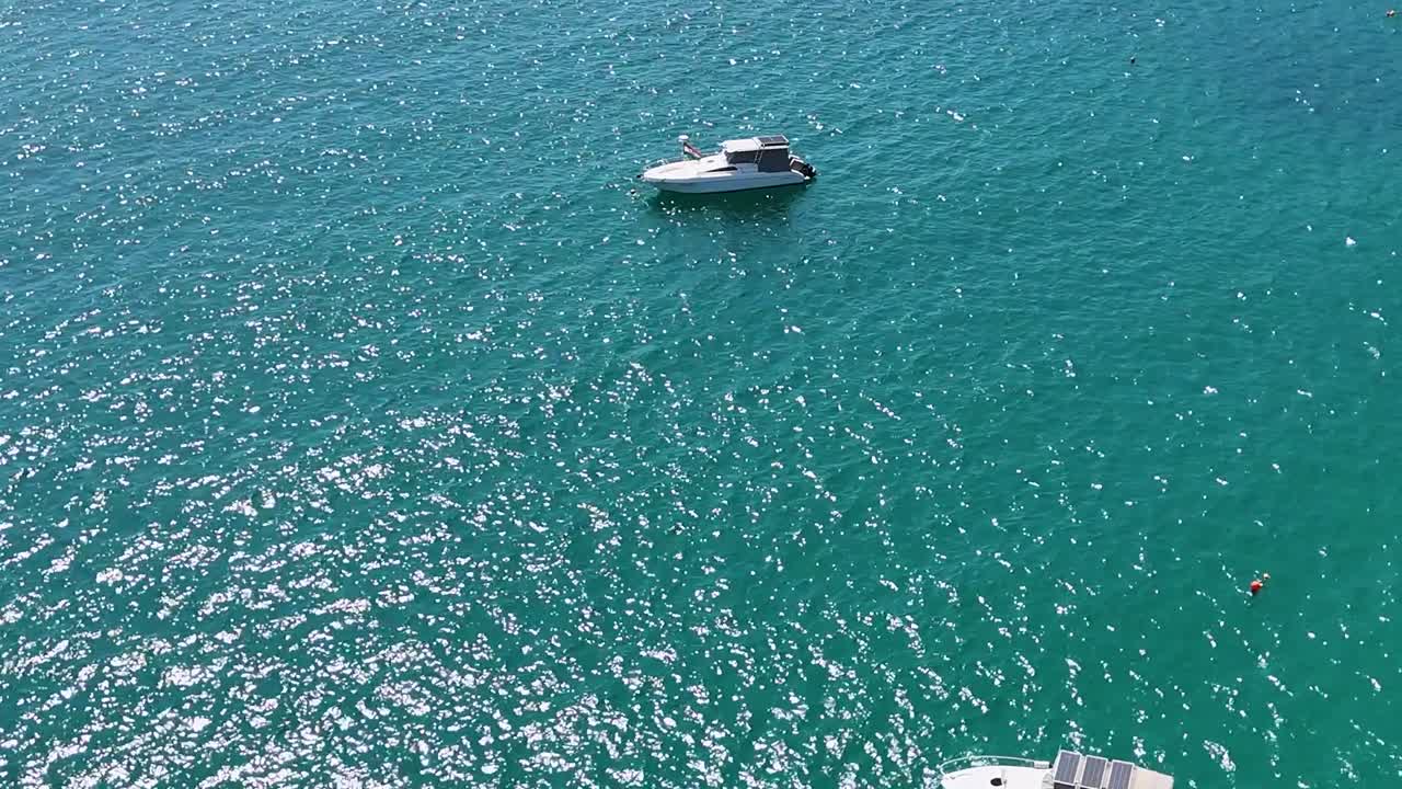 Riprese drone catturano barche che galleggiano su acque turchesi vicino a Capo Promthep, Phuket, in pieno giorno con un leggero movimento della telecamera.