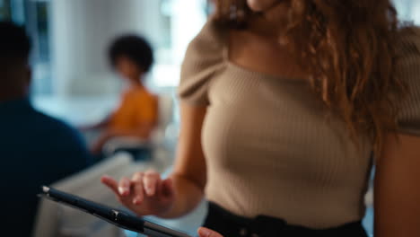 retrato de una joven mujer de negocios sonriente con una tableta digital de pie y trabajando en una oficina moderna