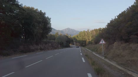conducir un automóvil en la carretera costera de córcega durante la luz del atardecer