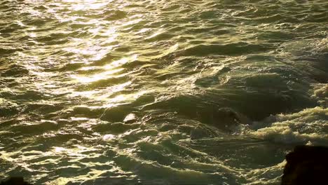 waves engulfing rocks on the volcanic coast of tenerife on a late after noon during the golden hour at sun set