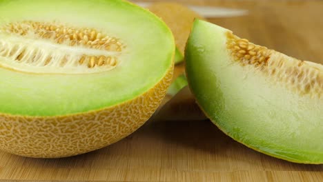 tracking shot of a juicy galia melon, on a bamboo cutting board