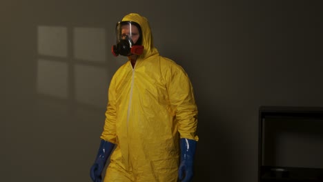 hombre vestido con traje de materiales peligrosos explora una habitación llena de humo