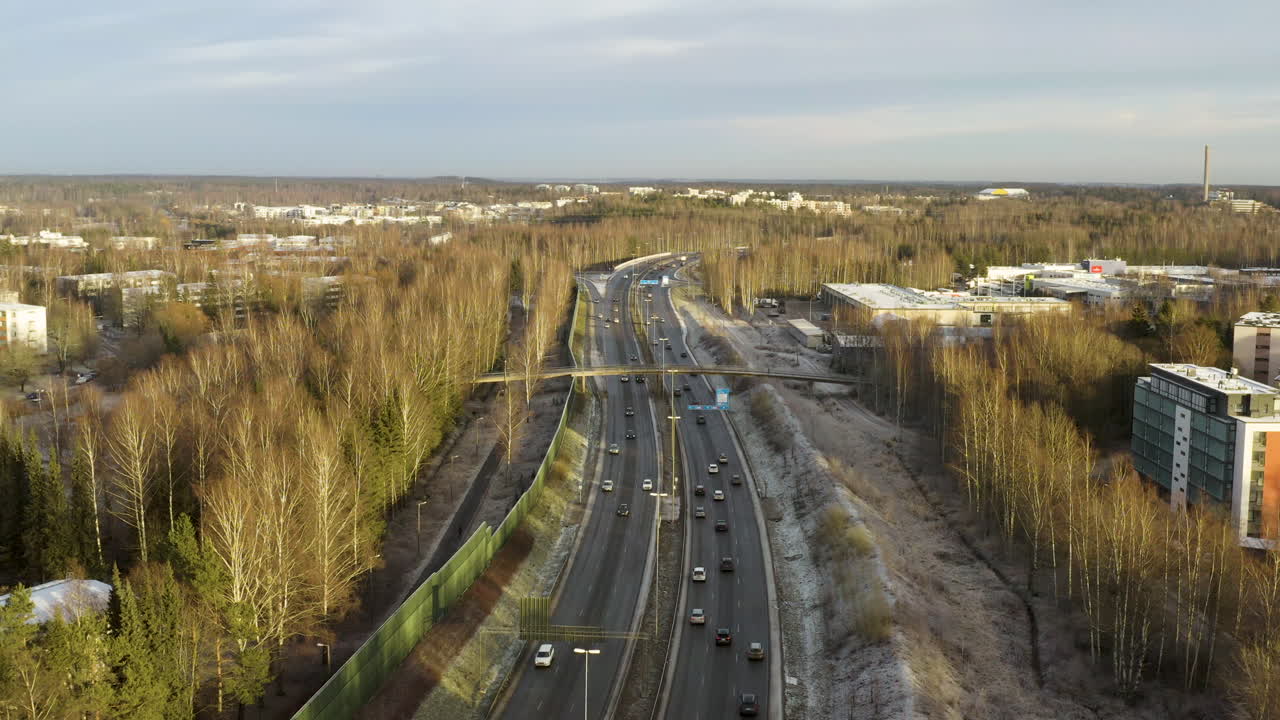 Aerial, static, drone shot overlooking traffic on the highway Vihdintie 120, sunny, fall evening, in Pitajanmaki, Helsinki, Finland