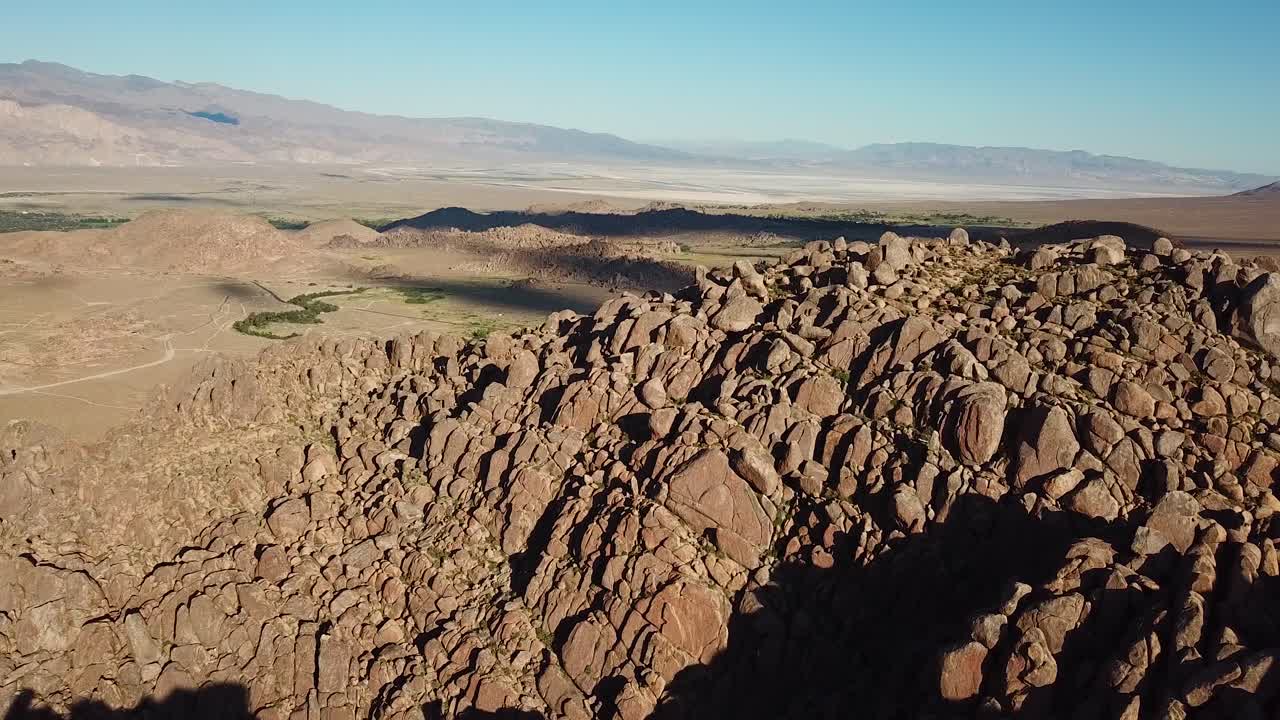 colina rocosa escarpada y desierto bajo cielo despejado y sol vespertino, vista aérea de drones