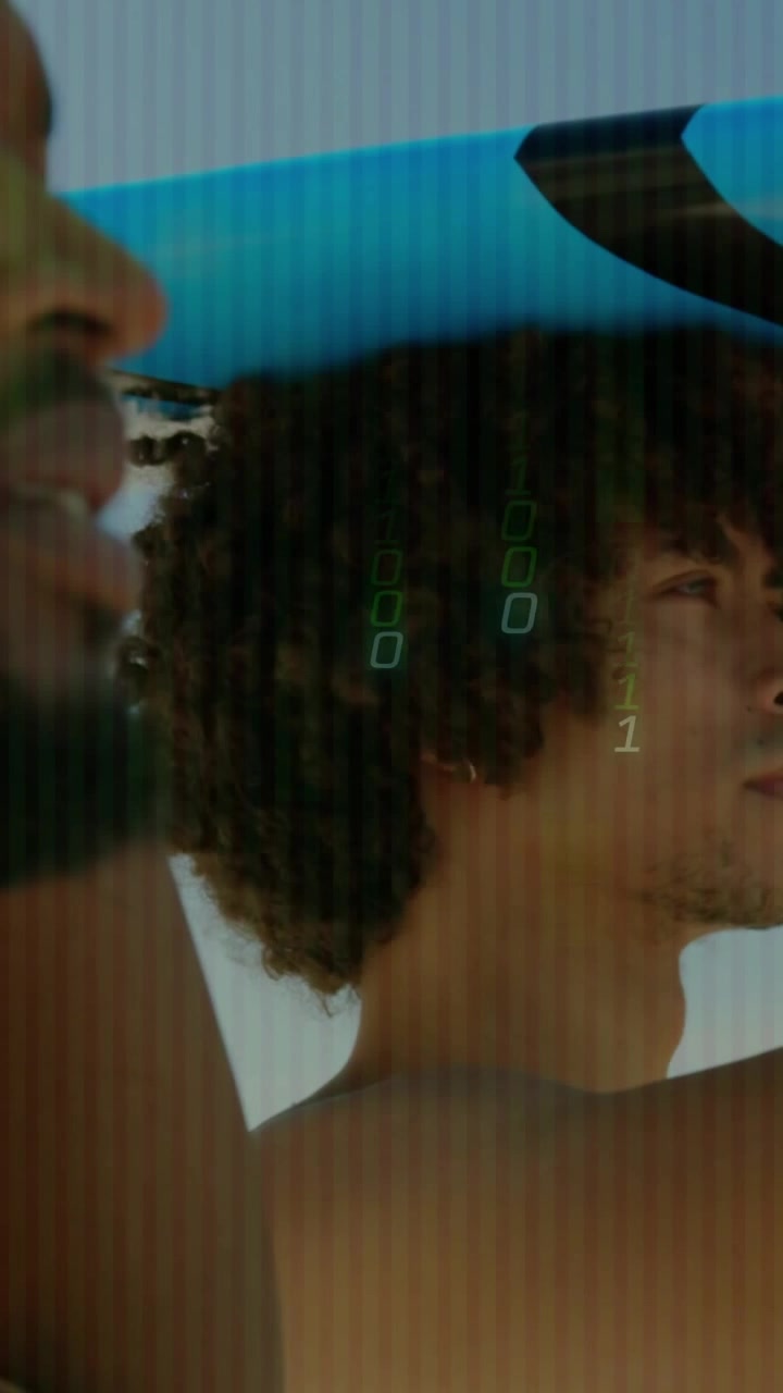 Vertical video: Men holding blue board, camera panning, green binary tech overlaying, prepping surf