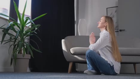 a young blonde does yoga sitting in the lotus position at home in the middle of the living room a young blonde does yoga sitting in the lotus position at home in the middle of the living room healthy lifestyle