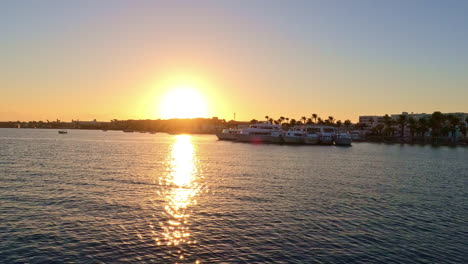 sol brillante durante la puesta de sol reflejándose en el mar en calma cerca del puerto deportivo