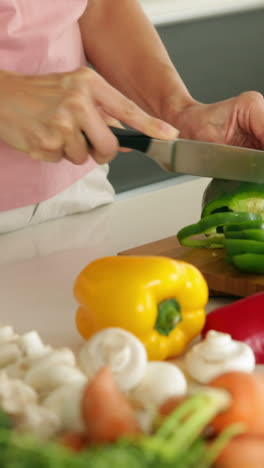 woman slicing green pepper and smiling at camera