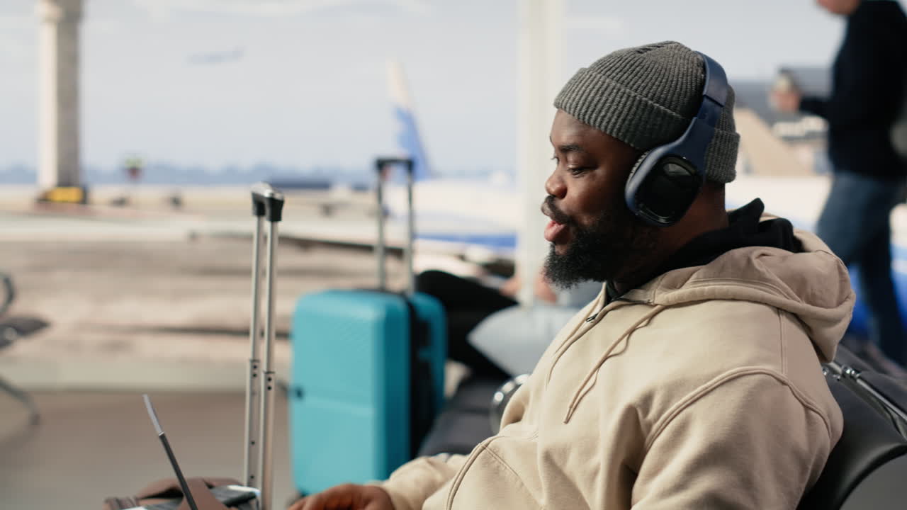 Giovane uomo in videochiamata con il laptop al terminal dell'aeroporto.