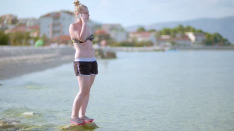 Junge-Dame,-Die-Am-Strand-Sitzt,-Während-Sie-Ihr-Mobilgerät-Benutzt-6-Using