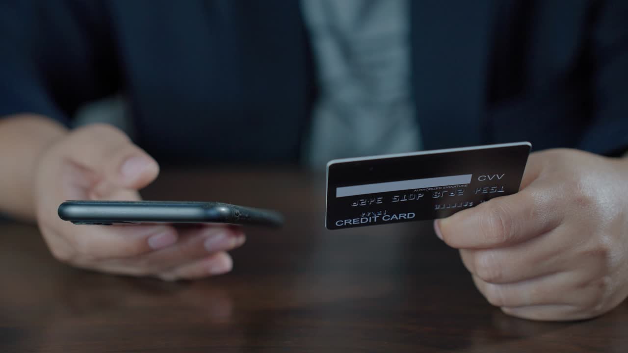 banca en línea con teléfono inteligente para comprar. manos sosteniendo una tarjeta de crédito mientras presiona el número de identificación en el móvil desde la tarjeta de crédito para comprar en línea. pago fácil usando móvil. imágenes b roll movimiento lento 4k.