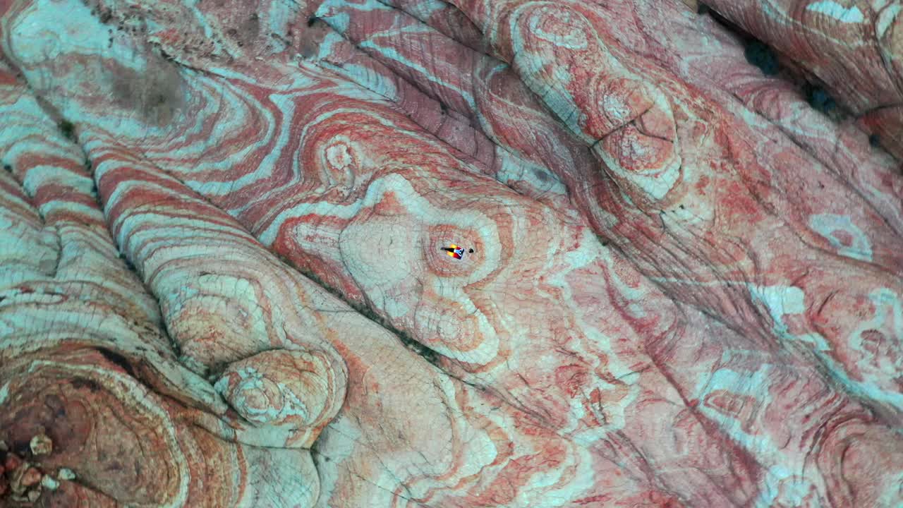 Moving away in a circle from a woman lying on a blanket in the mountains on colorful rocks