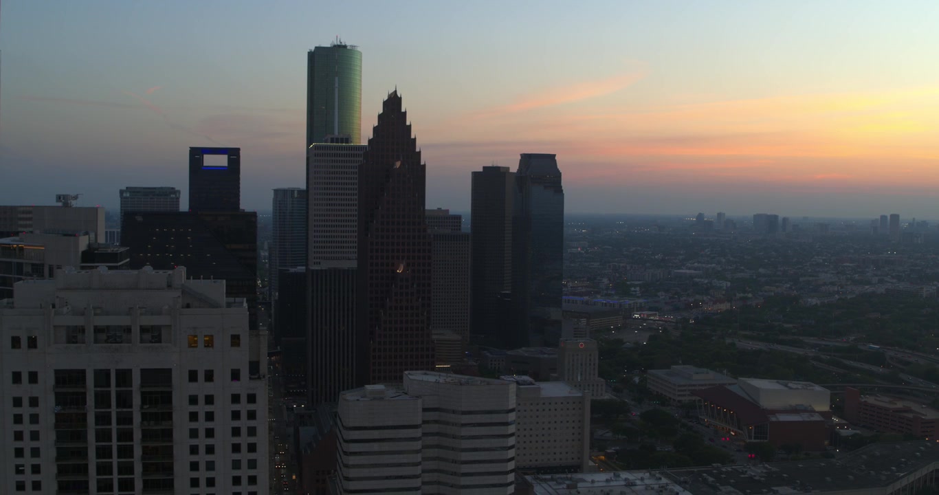 Vista aérea con dron del centro de Houston, Texas, mostrando modernos rascacielos y torres de oficinas durante el atardecer y la hora azul.