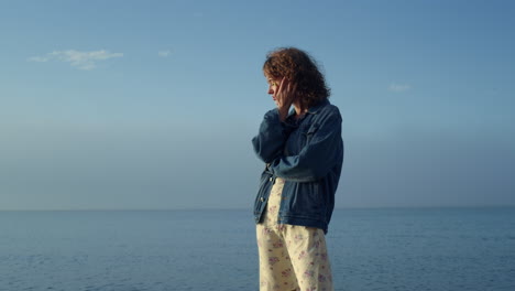 Stilvolle-Frau-Posiert-Am-Meeresstrand.-Verträumtes-Mädchen,-Das-Lockiges-Haar-Berührt