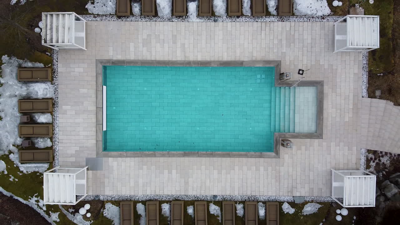 En opvarmet pool på et alpint luksusresort bliver mere blå, mens dronen stiger lige op