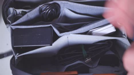 Hand-Putting-The-Cellphone-Accessories-In-Neat-Compartments-Of-Black-Bag-Organizer---Closeup-Shot