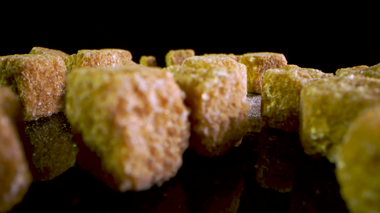 검은색 거울 표면에 떨어지는 갈색 설탕 조각의 클로즈업