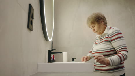 mujer anciana lavándose las manos en el baño