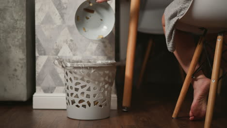 person throwing food scraps into a trash can