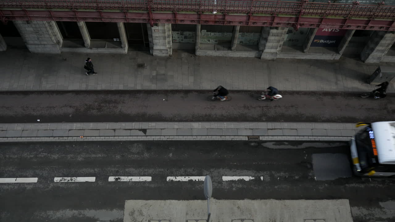 Many cyclist and buses driving on the street in city beside train station,aerial