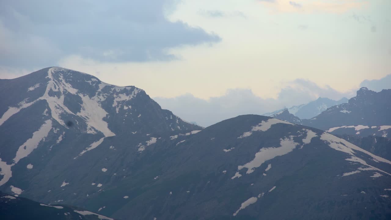 Static view of foggy mountains, snow on top on a cloudy day, copy space