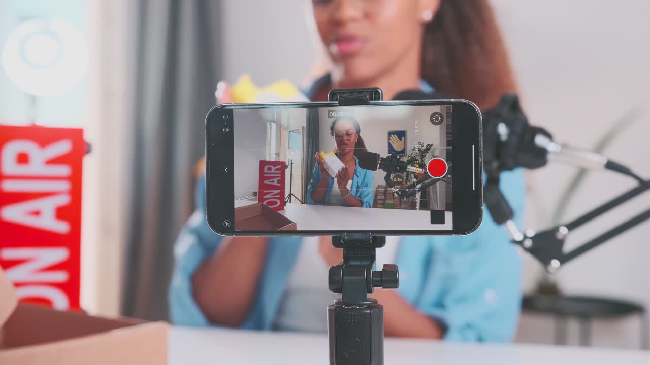 Giovane e carismatica donna afroamericana registra un video unboxing con la fotocamera del telefono