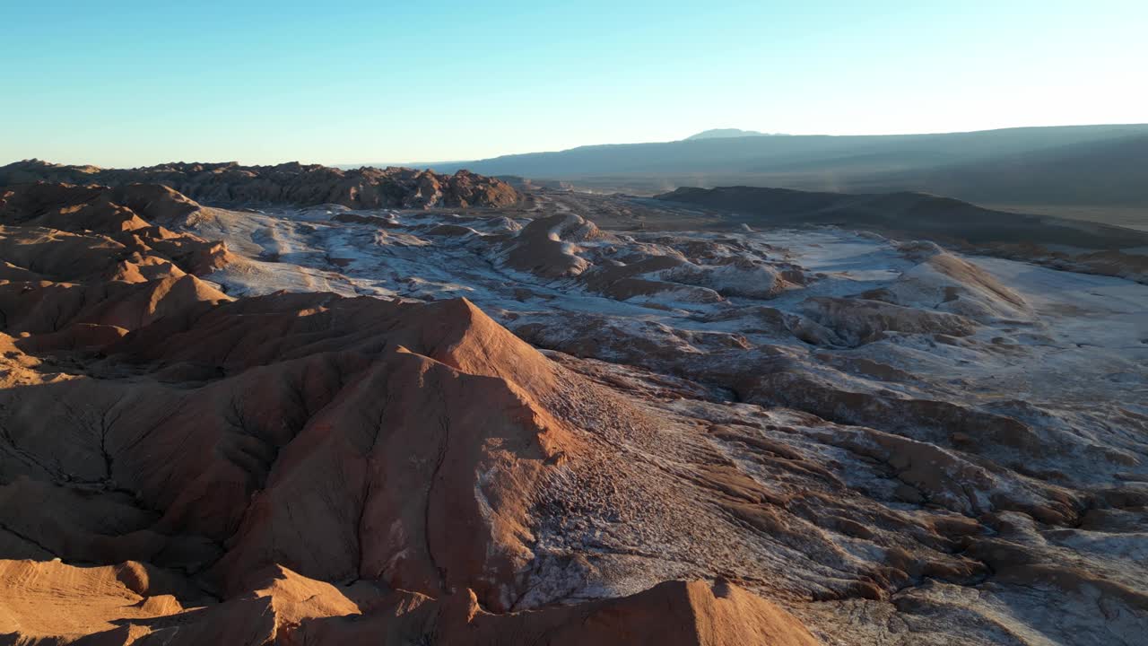 Sunset illuminating Valle de la Luna’s barren ridges and expansive white salt-covered valleys, captured by drone