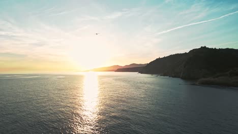 aerial view of coastline during sunset with small plane moving away