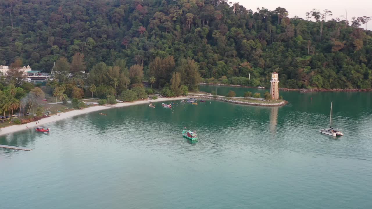 vuelo inverso sobre el estrecho de malaca con vistas al faro del muelle de perdana adecuado en un promontorio con hermosos paisajes naturales y yates y barcos de pesca amarrados en el agua