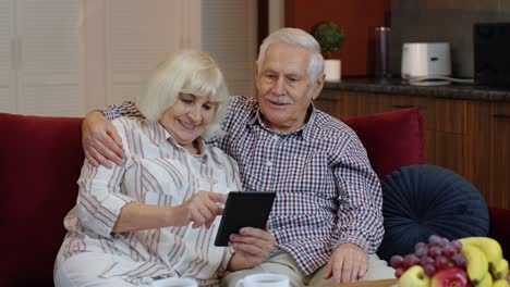 Abuelos-De-Pareja-De-Ancianos-Hablando-Y-Usando-Una-Tableta-Digital-En-Casa.-Compras-Por-Internet