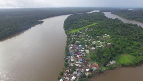 aerial drone footage flying over remote village alongside the river in south america