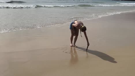 girl drawing in the sand on the beach