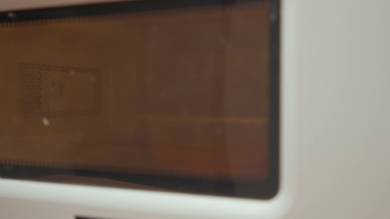 Dark rectangular panel recessed in light beige housing, shown with subtle movement, soft reflections, blurred edges, and gentle focus shift, creating clean industrial detail and muted color contrast